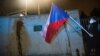 Демонстрант држи знаме на Република Чешка пред sид на руската амбасада во Прага, испрскан со кечап за време на протестот организиран од група активисти, Прага, на 17 април 2021 година.