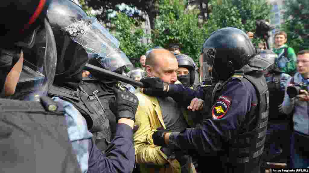 Резеңке таяқ ұстаған полиция наразылардың бірін тоқтатуға тырысып жатыр. 