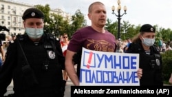 Руската полиција приведува опозициски активист со плакат „Паметно гласање“ за време на протестот во центарот на Москва, 14 август 2021 година