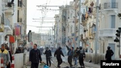 Riot police and rioters on a main square in the capital, Tunis, on January 13