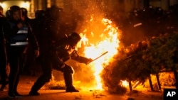 Poliția încearcă să stingă un incendiu, în timp ce susținătorii lui Călin Georgescu protestează după ce BEC a respins candidatura acestuia pentru alegerile prezidențiale din mai, București, 9 martie 2025.