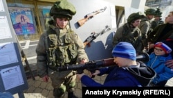 Copii se joacă cu echipamente militare la o celebrare a Zilei Apărătorului Patriei ruse în Simferopol, Crimeea, în februarie 2020.