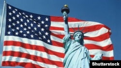 Статуя Свободи на тлі державного прапора США. 