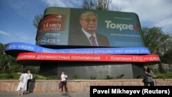 Люди рядом с монитором, на котором транслируют предвыборный ролик президента и кандидата в президенты Казахстана Касым-Жомарта Токаева. Алматы, 3 июня 2019 года.