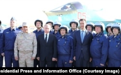 Ruski predsjednik Vladimir Putin i tadašnji sirijski predsjednik Bašar al-Asad poziraju za fotografiju s ruskim pilotima u bazi Hmeimim, decembar 2017.