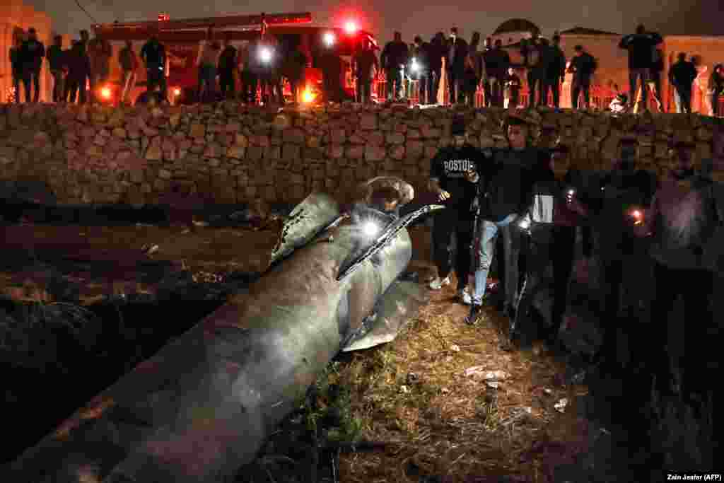 Palestinians in Ramallah gather around a fallen rocket after the Iranian attack. 