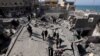 Mai mulți palestinieni inspectează locul unui atac israelian asupra unei clădiri rezidențiale, în Deir Al-Balah, în centrul Fâșiei Gaza, 18 martie 2025. 