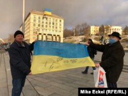 Олександр Антоновец и уште еден човек кој го даде само своето име, Олександр, стојат на плоштадот на независноста во Киев, држејќи украинско знаме со потписи од луѓе кои се бореле во Донбас против сепаратистите поддржани од Русија.
