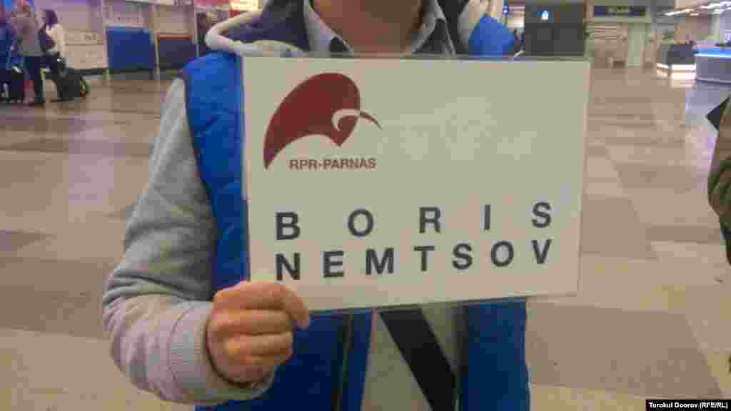 Гражданский активист держит табличку "Борис Немцов" в зале ожидания пассажиров рейсов, прилетающих из России. Прага, 2 апреля 2015 года. 