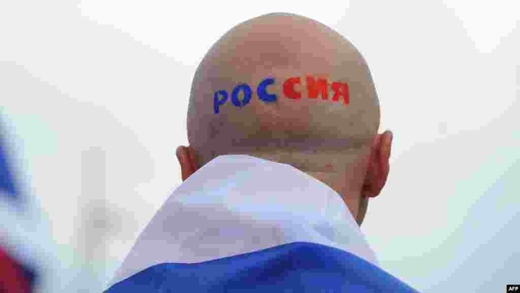 A Russian football fan with "Russia" painted on his head outside the stadium in Warsaw