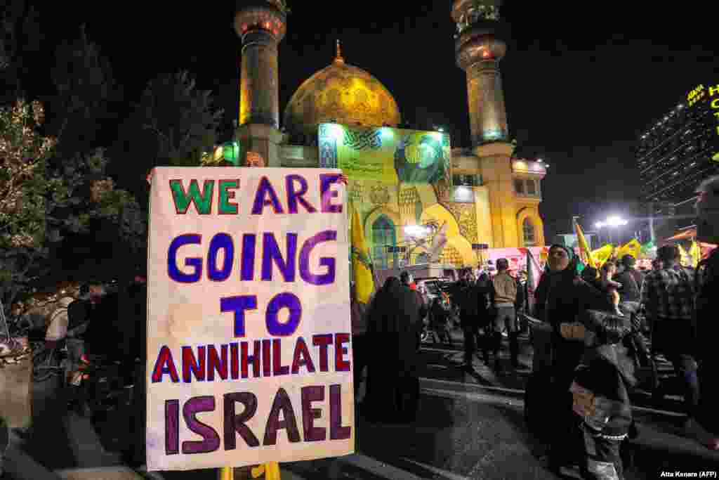 An man holds a sign in Tehran as crowds in the Iranian capital celebrate the rocket attacks. Israel has vowed to respond to the strikes, with Prime Minister Benjamin Netanyahu calling them "a big mistake," which Tehran "will pay for." 