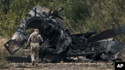 Український військовослужбовець біля знищеного в бою російського танка на звільненій території біля міста Балаклеї в Харківській області, 11 вересня 2022 року 