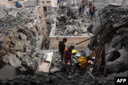 Medici palestinieni caută printre dărâmături în urma atacurilor israeliene asupra unor apartamente de pe strada Yarmuk din orașul Gaza, 24 aprilie 2025.