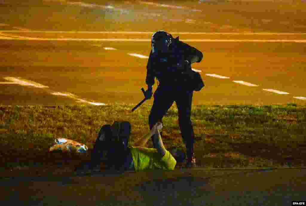 Policajac stoji nad muškarcem na terenu u Minsku 12. augusta.