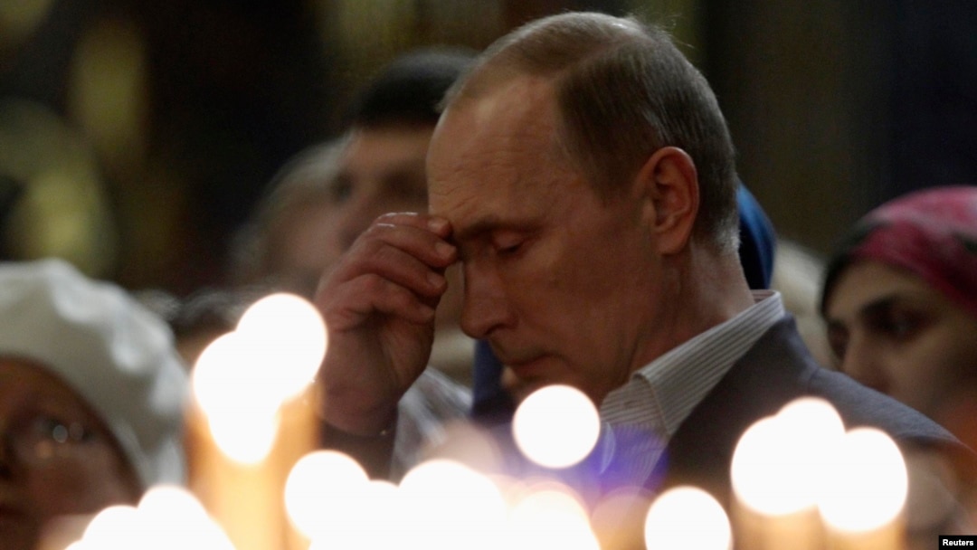 Russian President Vladimir Putin crosses himself as he attends an Orthodox Christmas service at the Holy Face of Christ the Savior Church in the southern Russian city of Sochi early on January 7.