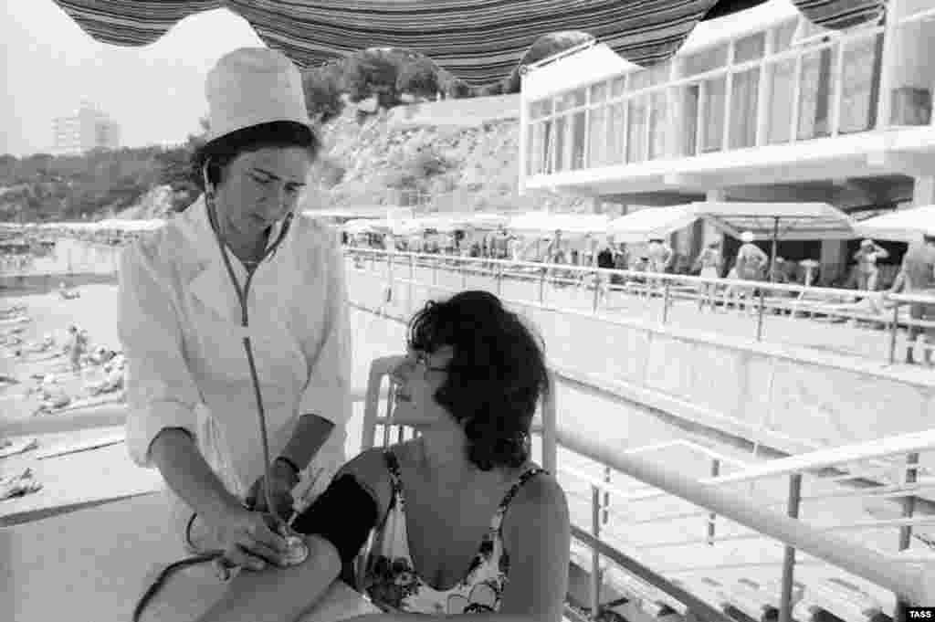 1977 год: медсестра на пляже санатория "Украина" осматривает женщину, приехавшую в Крым из Кабардино-Балкарии.