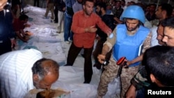 A UN observer takes pictures of the bodies of people whom antigovernment protesters say were killed by government security forces in Houla. The dead included 49 children and 34 women.