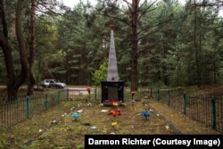 Новошепеличи, Украйна. Обелиск с надпис: „Тук бяха погребани жители на съседни села, загинали от ръцете на фашистки нашественици по време на Великата отечествена война. 1941-1945 “. Село Новошепеличи до голяма степен е потънало в гората, след като е било силно замърсено по време на ядрената катастрофа, но паметникът изглежда добре поддържан от бивши жители.