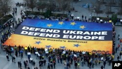 Aktiwistler Brýusselde geçiriljek sammitiň öňüsyrasynda, Ýewropa Geňeşiniň binasynyň daşynda Ukrainany goldamak üçin uly baýdak açýarlar. 5-nji mart, 2025 ý.