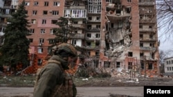 Украински военен е заснет пред разрушена от руските военни жилищна сграда в град Покровск.