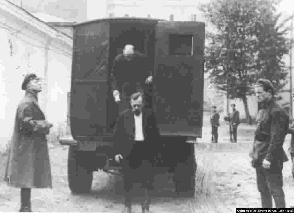 Заключенные выходят из грузовой машины, переоборудованной в автозак.
