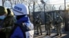 Grănicerii ucraineni stau de pază în timp ce observatorii OSCE trec punctul de control dintre teritoriul controlat de Kiev și zonele ocupate din estul devastat de război, în regiunea Lugansk.