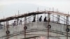 BOSNIA-HERZEGOVINA -- Residents pass over a more than 500-year-old bridge over the Neretva River, which is protected with wooden scaffolding, in the old part of the Bosnian city of Mostar, April 12, 1993