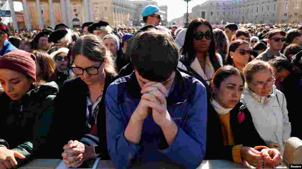 Oamenii se roagă în timp ce așteaptă începerea slujbei funerare a Papei Francisc.