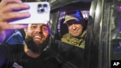Евгениј Пригожин седи во воено возило и позира за селфи фотографија со локален цивил на улица во Ростов на Дон, Русија, 24 јуни 2023 година, пред да замине од штабот на Јужниот воен округ.