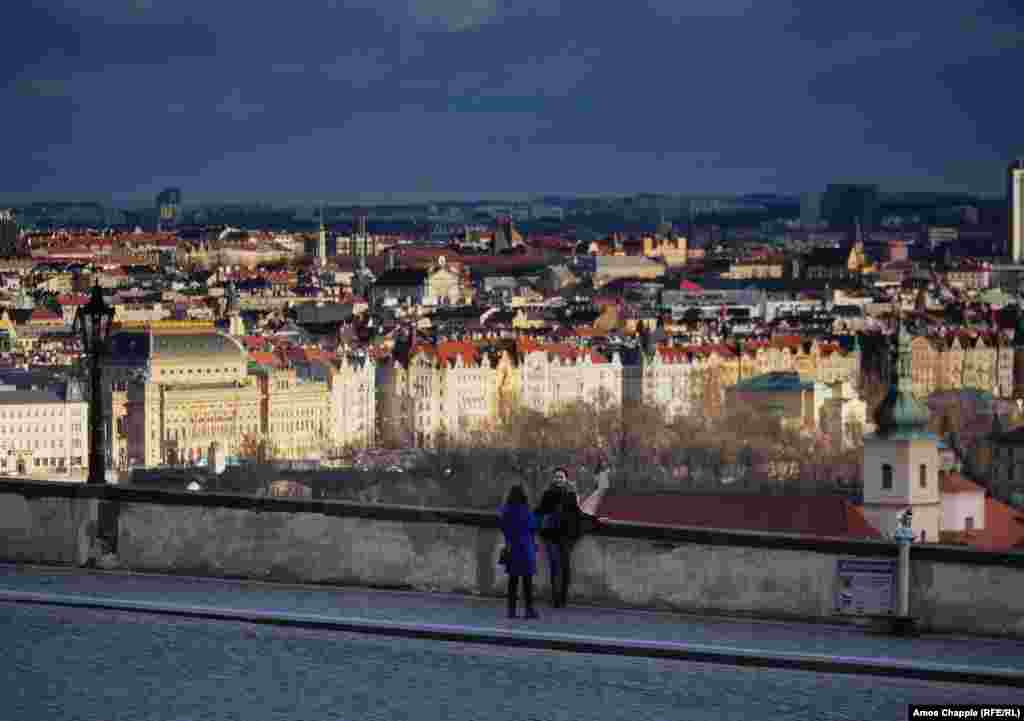Doi turiști se fotografiază în apropiere locul unde se poate vedea panorama orașului, loc de obicei extrem de aglomerat cu turiști. 