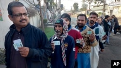 Ljudi drže svoje nacionalne legitimacije dok čekaju u redu da daju svoj glas na parlamentarnim izborima ispred biračkog mjesta u Multanu u Pakistanu 8. februara 2024.