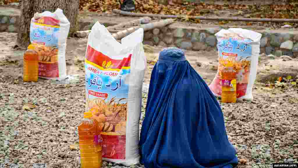 Žena sjedi pored pomoći u hrani koju distribuira lokalna dobrotvorna fondacija u Mazar-i-Sharifu, Afganistan. 
