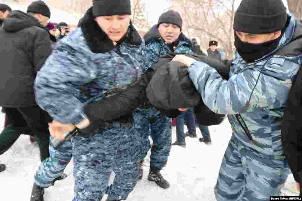 Арнайы жасақ наразылық белгіленген жерге келгендердің бірін әкетіп барады. 