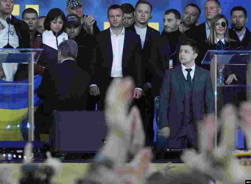 Кандидати в президенти Володимир Зеленський та Петро Порошенко стали на коліна на сцені НСК «Олімпійський» на знак пошани до родичів загиблих на Донбасі. Зеленський став на коліна, звертаючись до глядачів, а Порошенко опустився на коліно і поцілував державний прапор, який тримала волонтерка Тетяна Ричкова, чоловік якої загинув у 2014 році біля Єнакієвого. Київ, 21 квітня 2019 року
